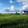 A large white house sits on a large grassy field